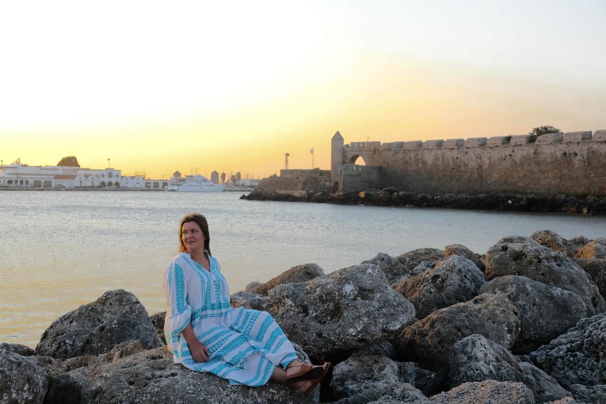 A Woman sitting alone on the rocks on a Greek island.