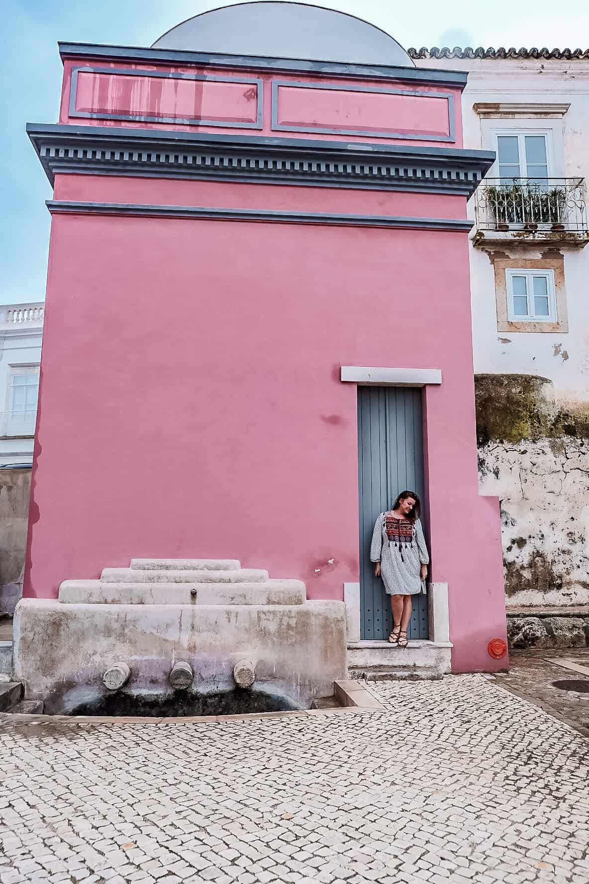 Standing in front of a bright pink building in Old Town Tavira Portugal.