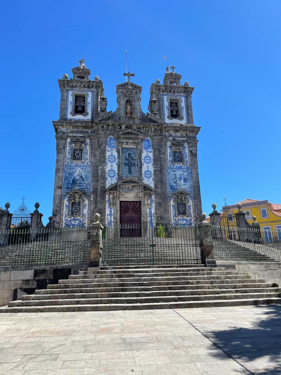 The iconic Santo Ildefonso Church in Porto stands majestically under a clear blue sky, its façade adorned with traditional Portuguese blue and white azulejos, a testament to the city's rich cultural heritage and a must-visit on a day trip from Faro.