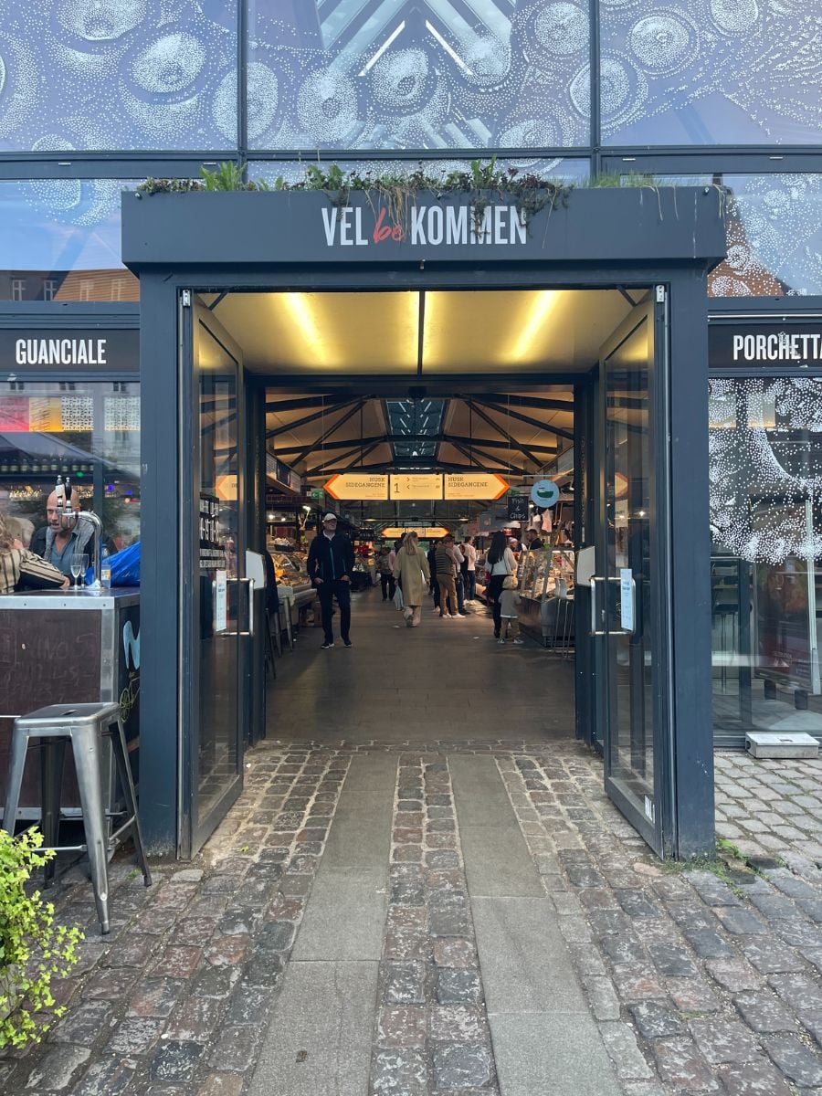 Entrance to Torvehallerne food market in Copenhagen with people browsing inside.