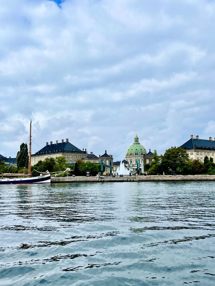 View of Copenhagen from the water with historic buildings and Frederik&rsquo;s Church in the background.