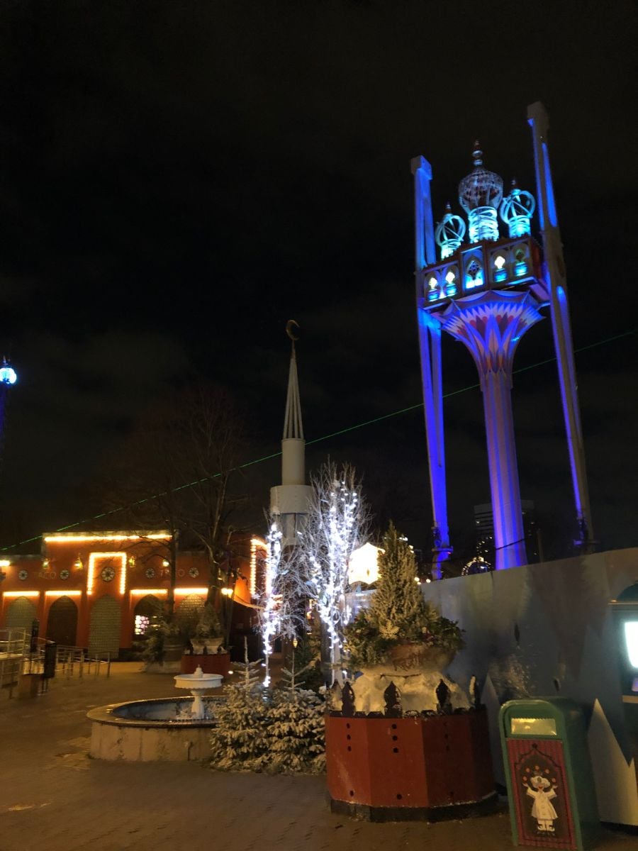 Night view of Tivoli Gardens in Copenhagen with illuminated tower and festive lights.