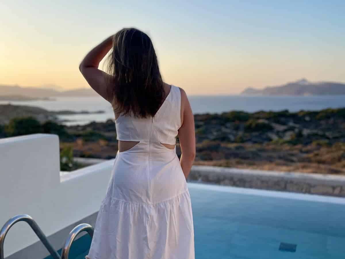 A solo female traveler gazes at the ocean on a Greek island.