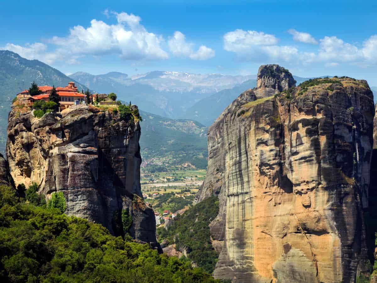 Meteora monasteries perched atop massive rock pillars, with a backdrop of the Pindus Mountains, a breathtaking and spiritual day trip destination from Athens.