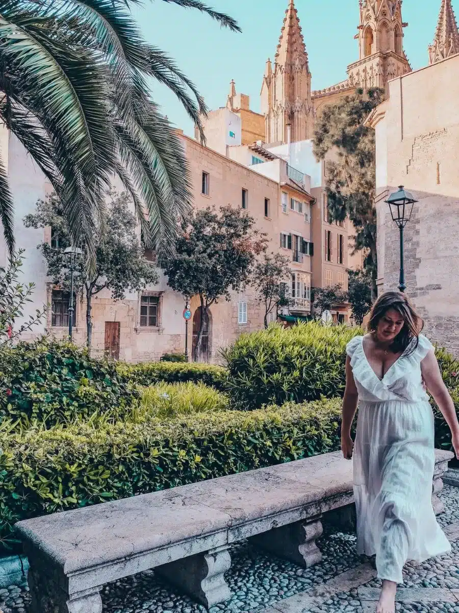 A serene solo traveler strolls through a historic quarter in Mallorca, with the island's iconic architecture in the background, embodying the charm and independence of solo travel.