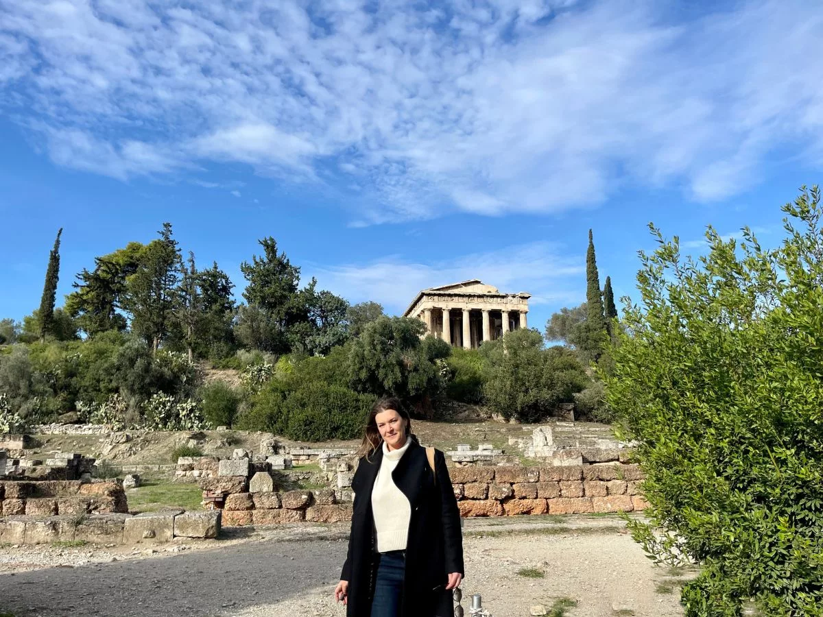 A woman walking by herself in Athens Greece with the ancient monuments in the background. 