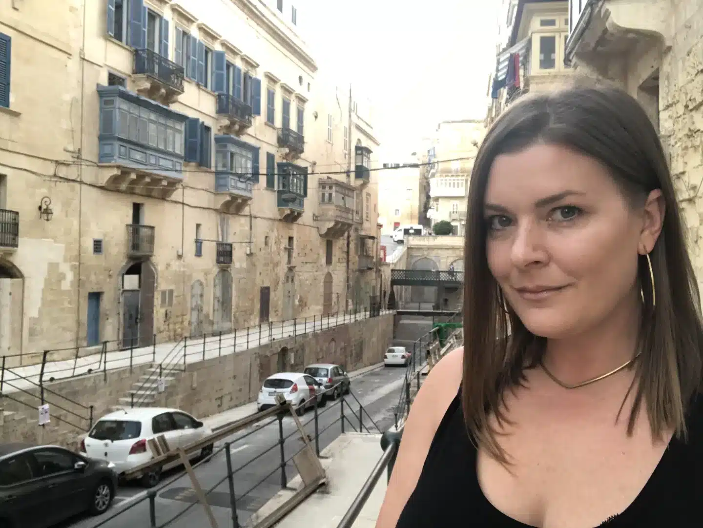 a woman on the streets of Malta with the ancient city behind her.