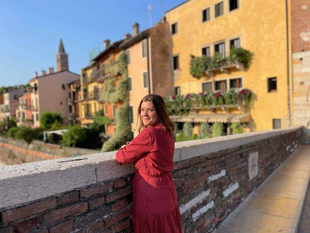 A Solo Woman Traveling in a red dress on a bridge in Verona