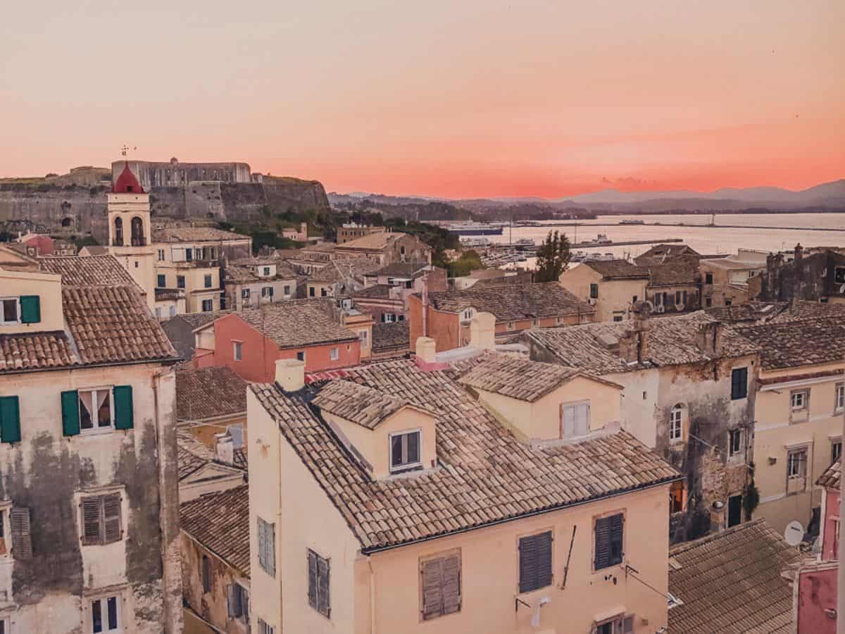 A view of Corfu town with a sunset of orange and pink colors