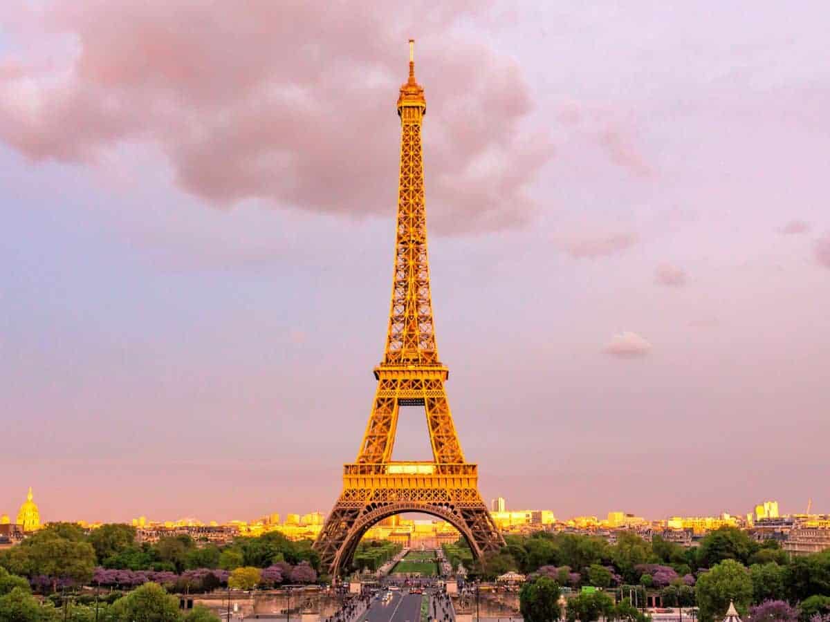 The Eiffel Tower dominates the Parisian skyline at dusk, its lattice structure illuminated against a pastel-colored sky—a quintessential symbol for anyone experiencing a solo trip to Paris.