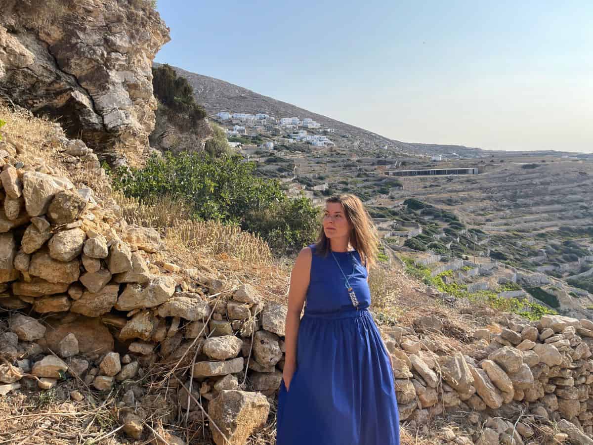 A woman in a blue dress on the Greek Island of Ios with mountains in the backgroun