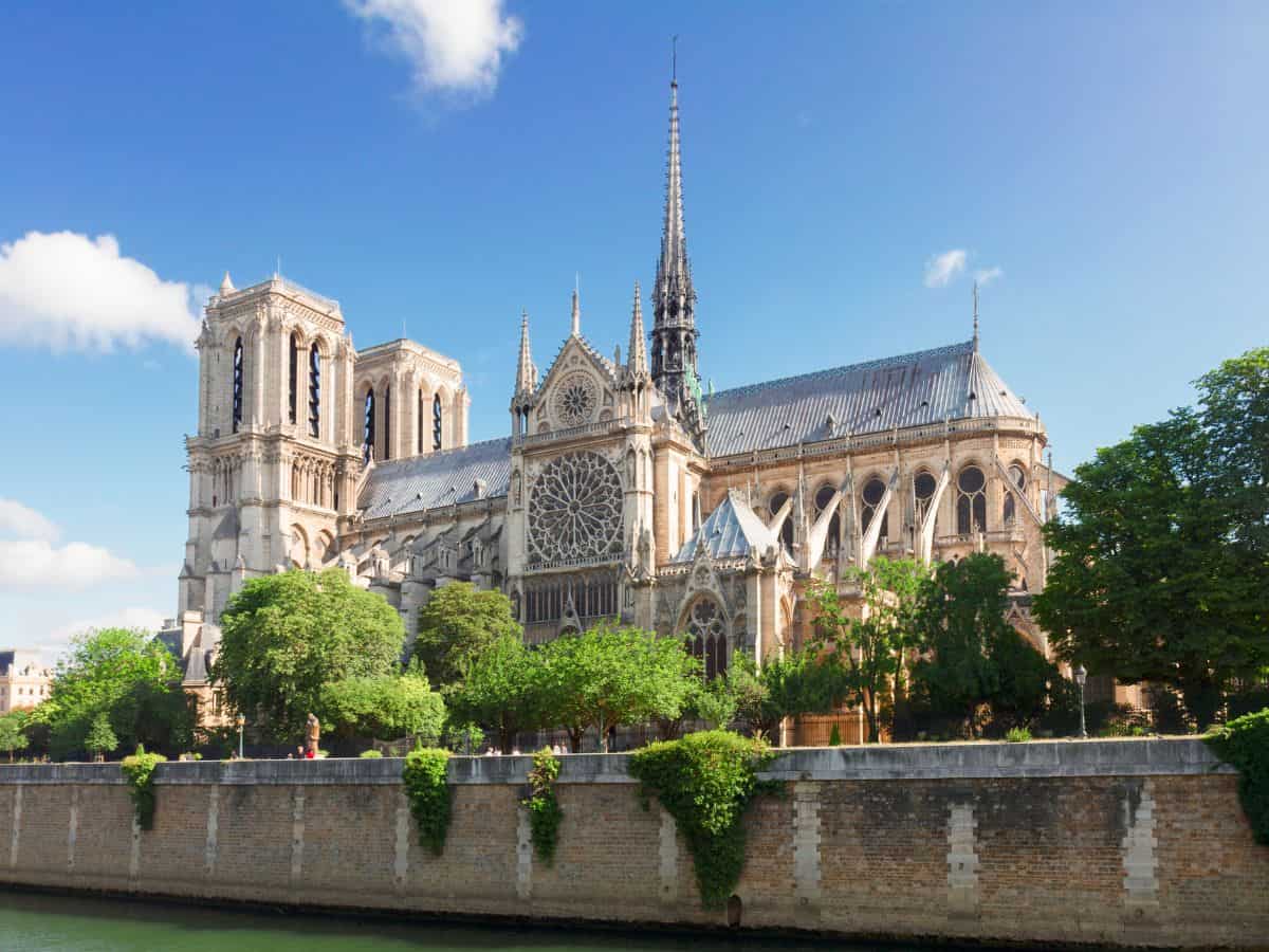 The majestic Notre-Dame Cathedral stands resplendent under a clear blue sky, as seen from across the Seine River, a must-visit landmark for anyone on a solo trip to Paris.