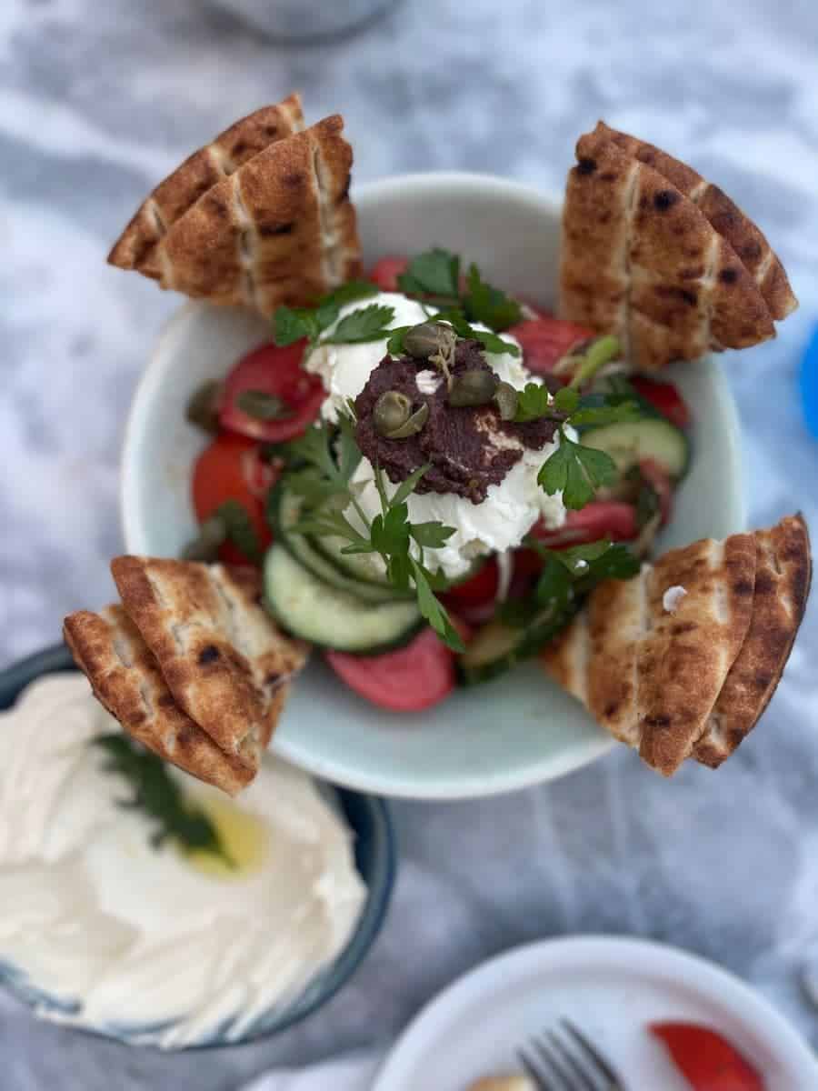 Up close of a greek salad with pita bread.