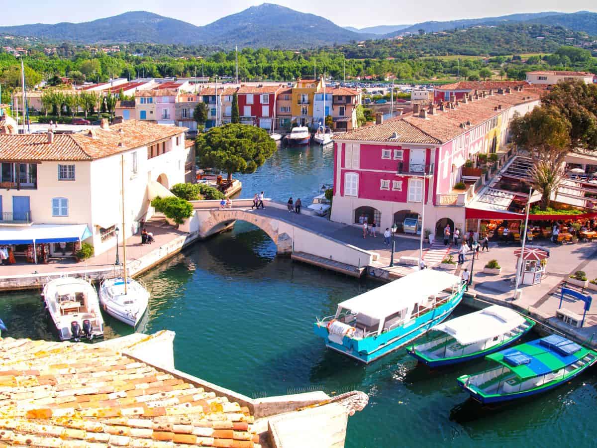 Colorful town of Grimaud, France with boats in the harbor with a small bridge connecting both sides of the town.
