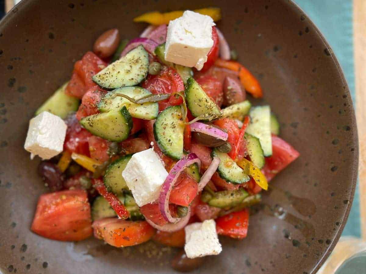 a greek salad of cheese, tomato, cucumber and onion