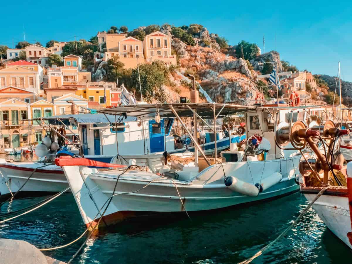 The fishing boats upclose with the colorful houses of Symi Greece in the background