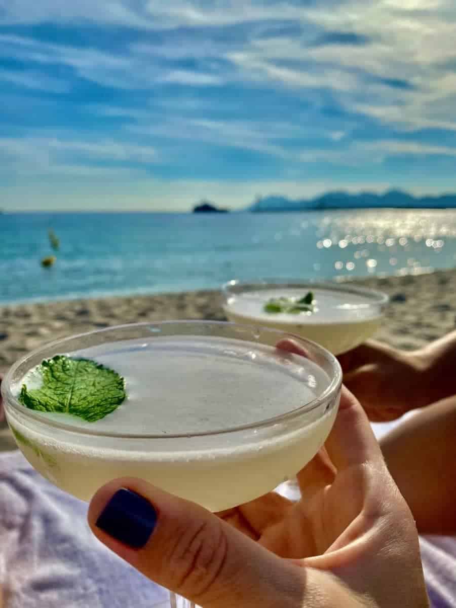 two cocktails in hand at the beach in Cannes