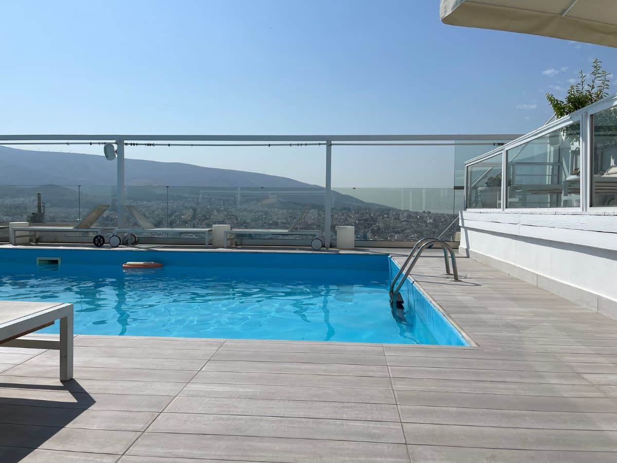 Wood decking and rooftop pool with view of Athens