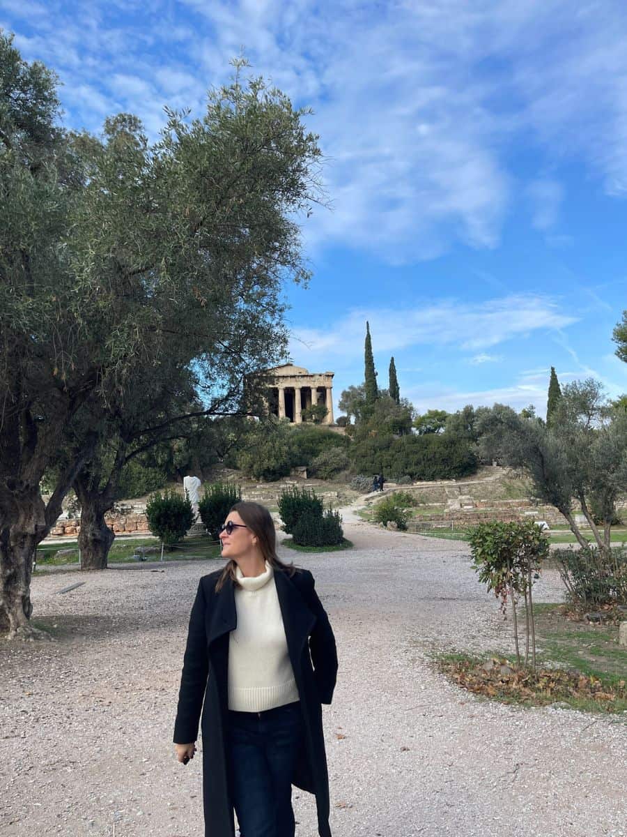 A woman in a coat and sweater exploring Athens in the month of December