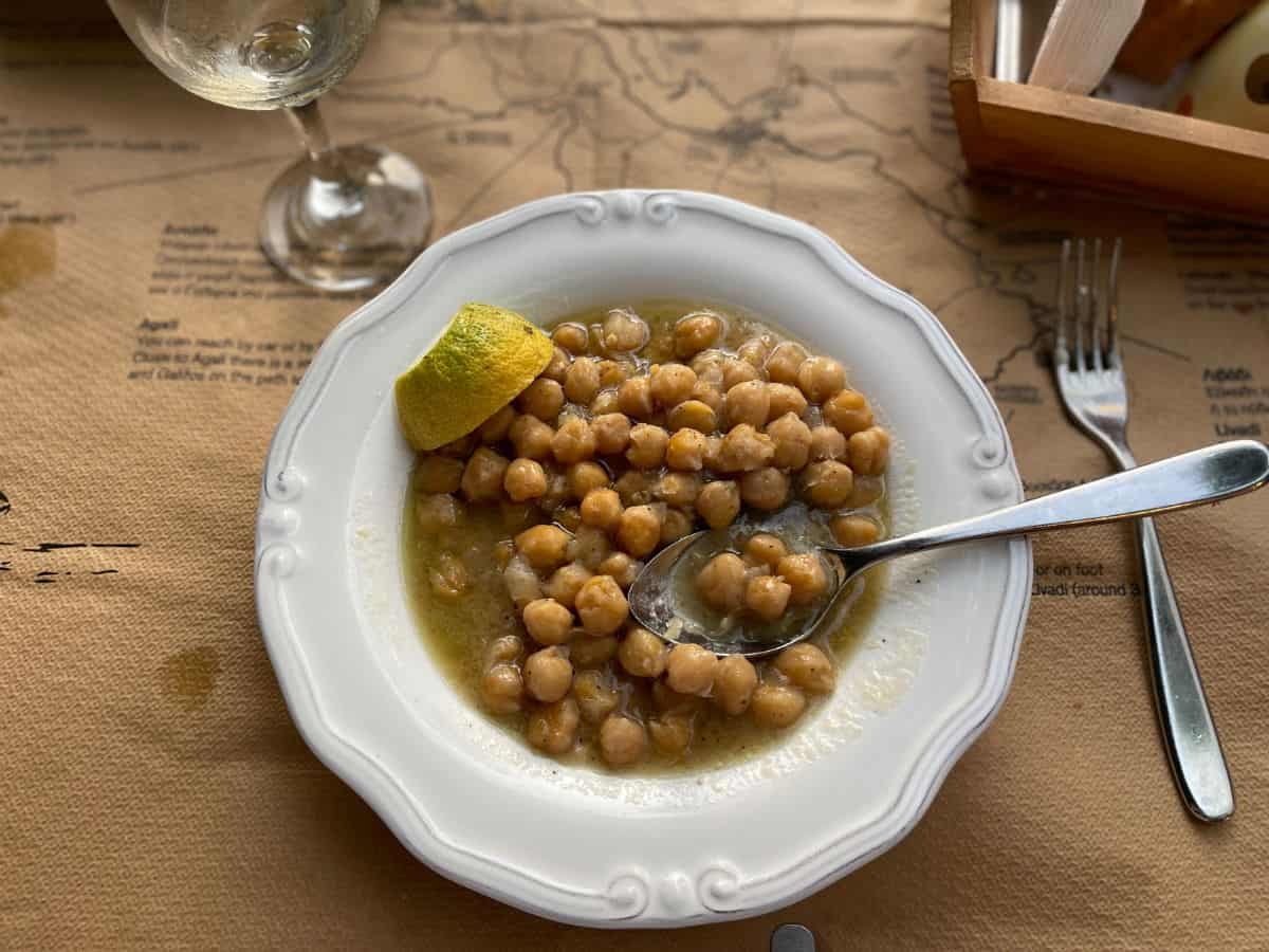 bowl of chickpeas with a glass of wine next to it.