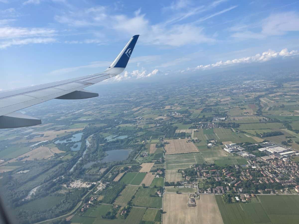 Airplane wing flying over Italy on my solo travel Milan trip