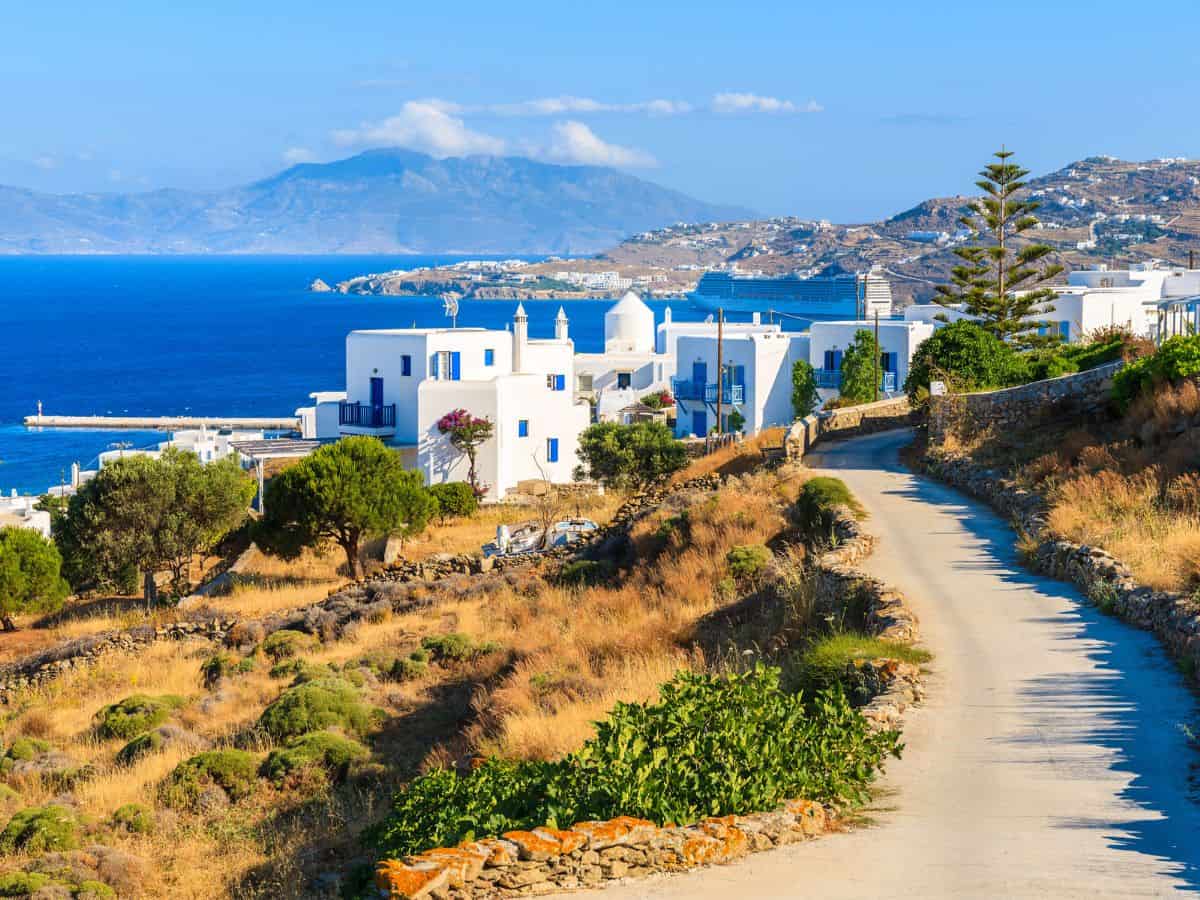 Picture of the road in Mykonos with the background of beautiful white houses and the ocean.