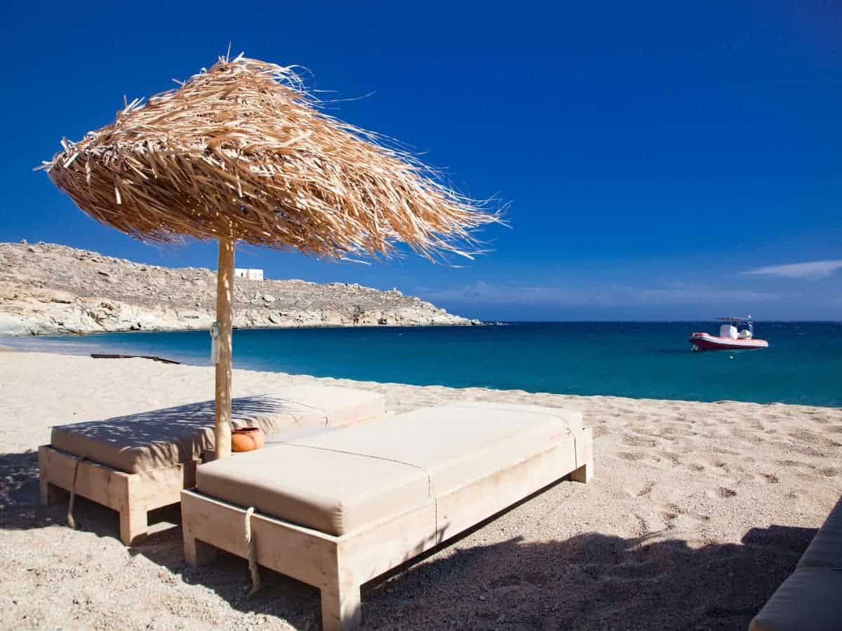 2 sunbeds in with a straw umbrealla that makes us ask the question: is Mykonos Expensive at the beach?