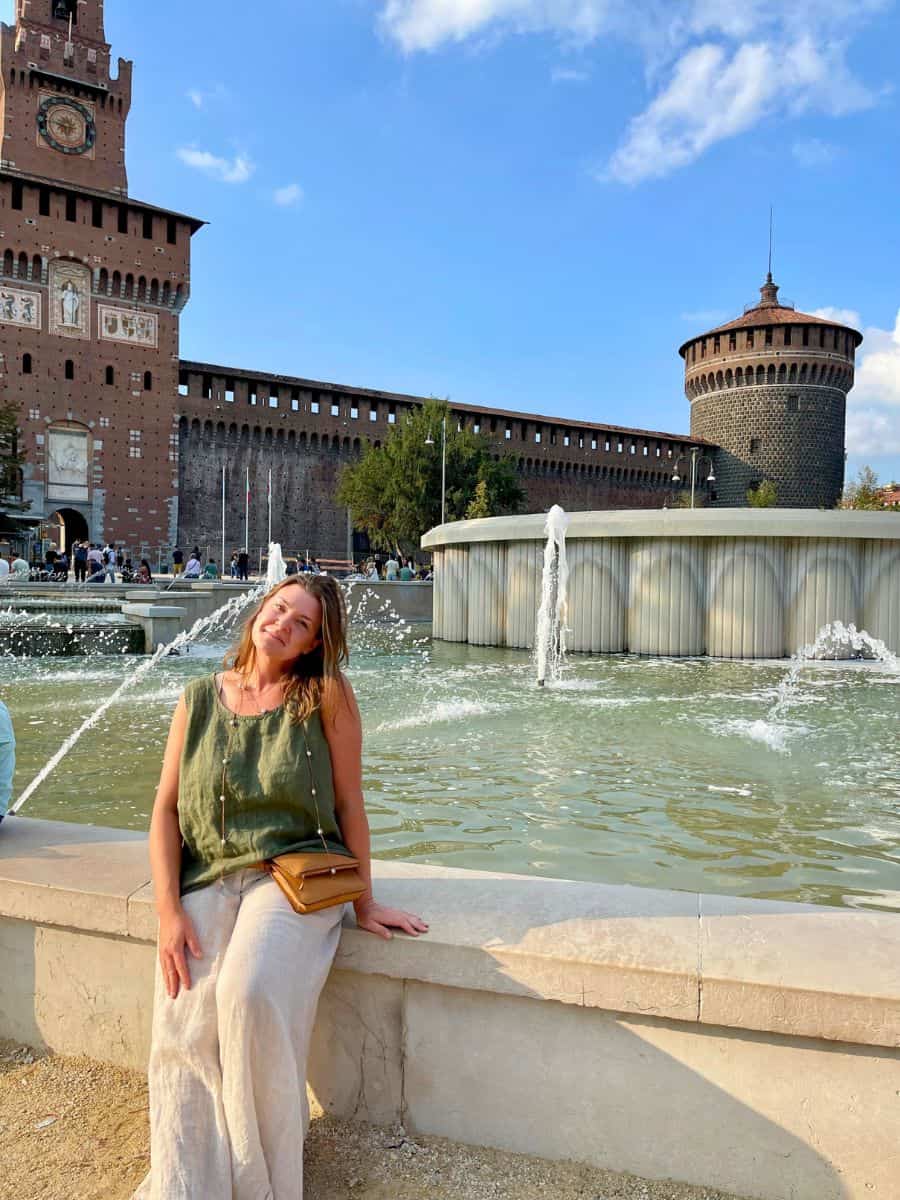 a woman sitting solo at the fountain in Milan. Milan solo travel activity of exploring the castle.