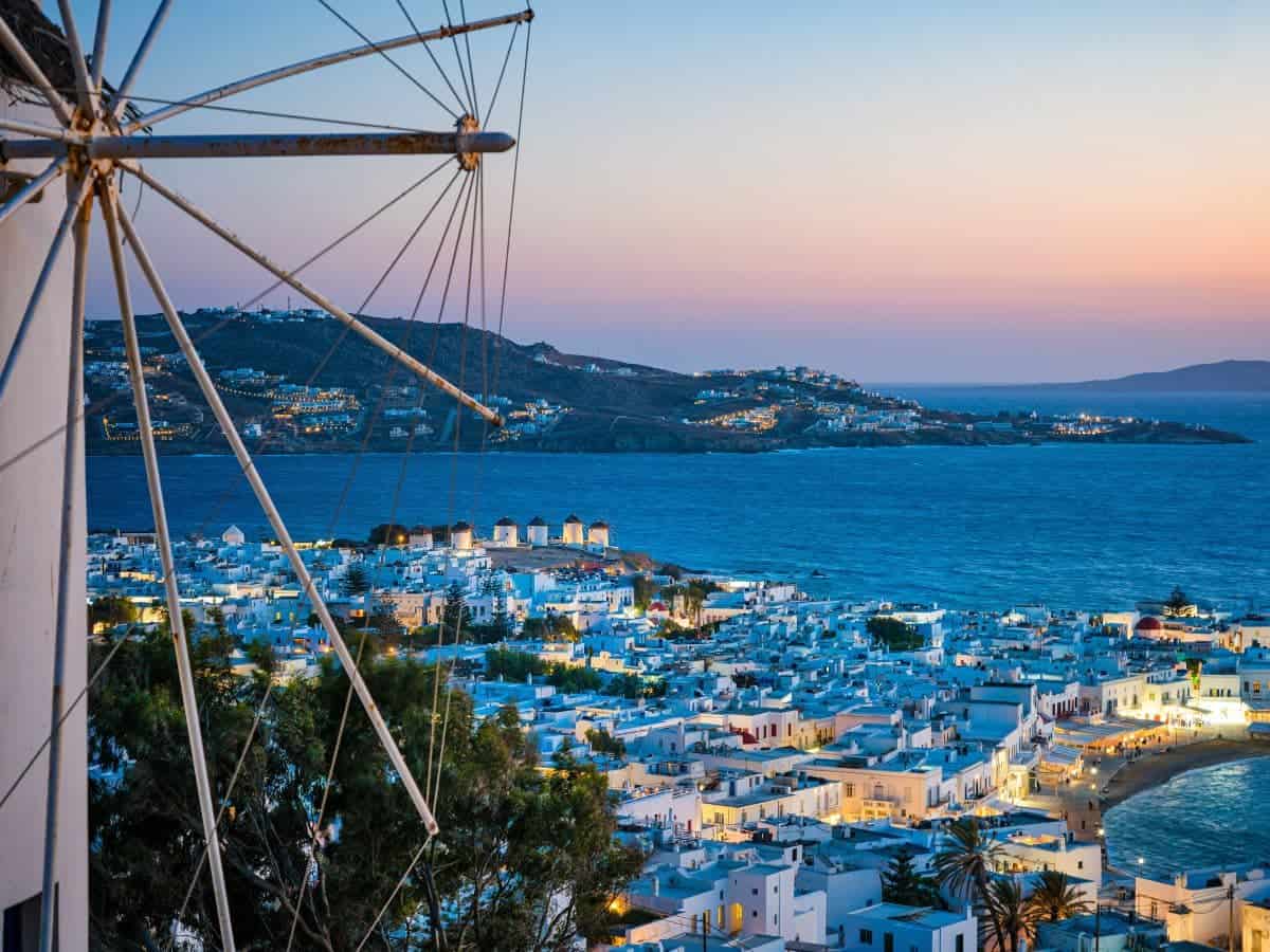 Sunset in Mykonos with the ocean, windmill and town below.