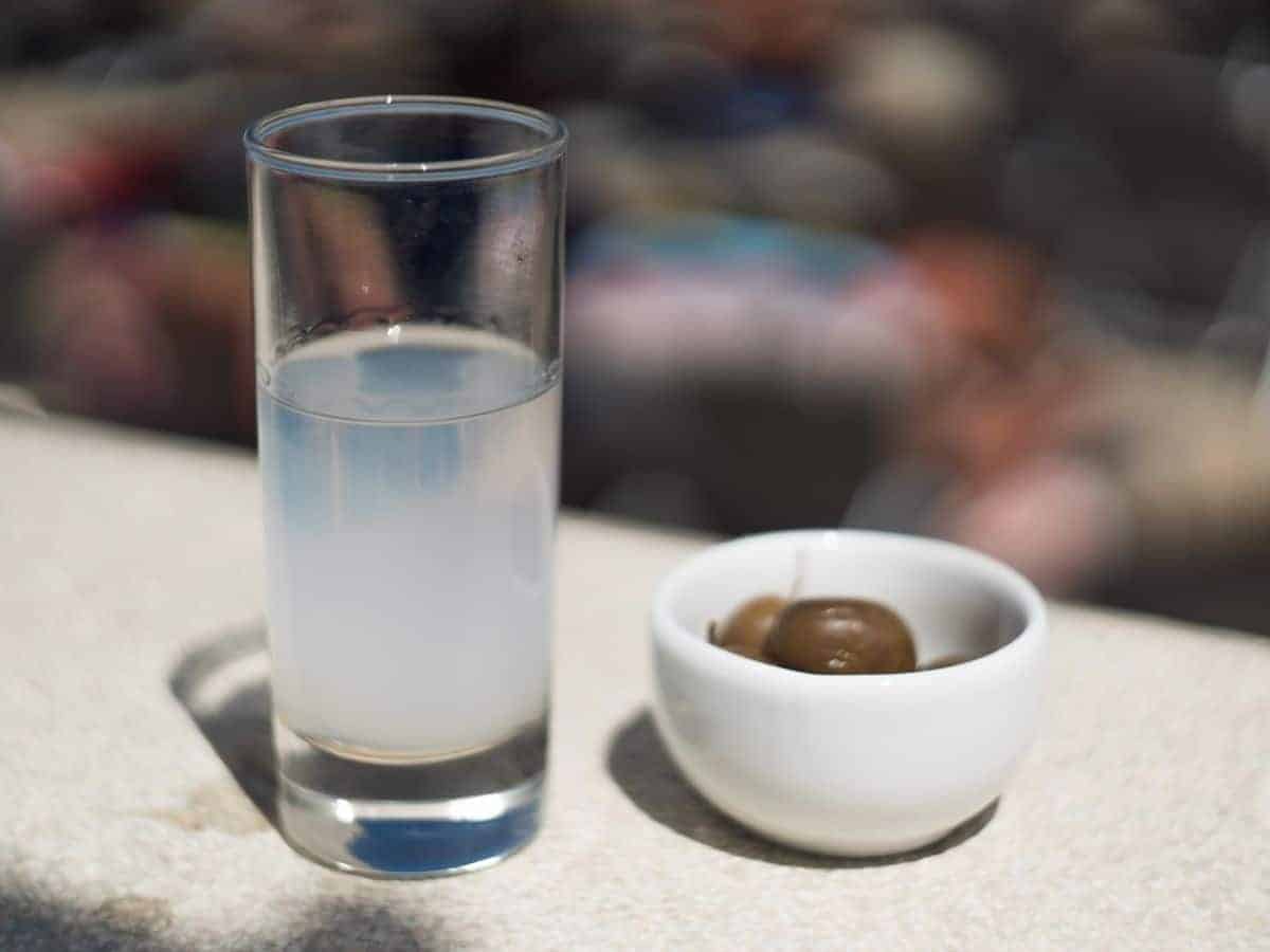A glass of Greek liquor Ouzo and a bowl with olives