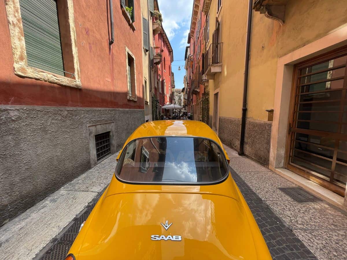 An old classic bright yellow car on the road in Verona, Italy