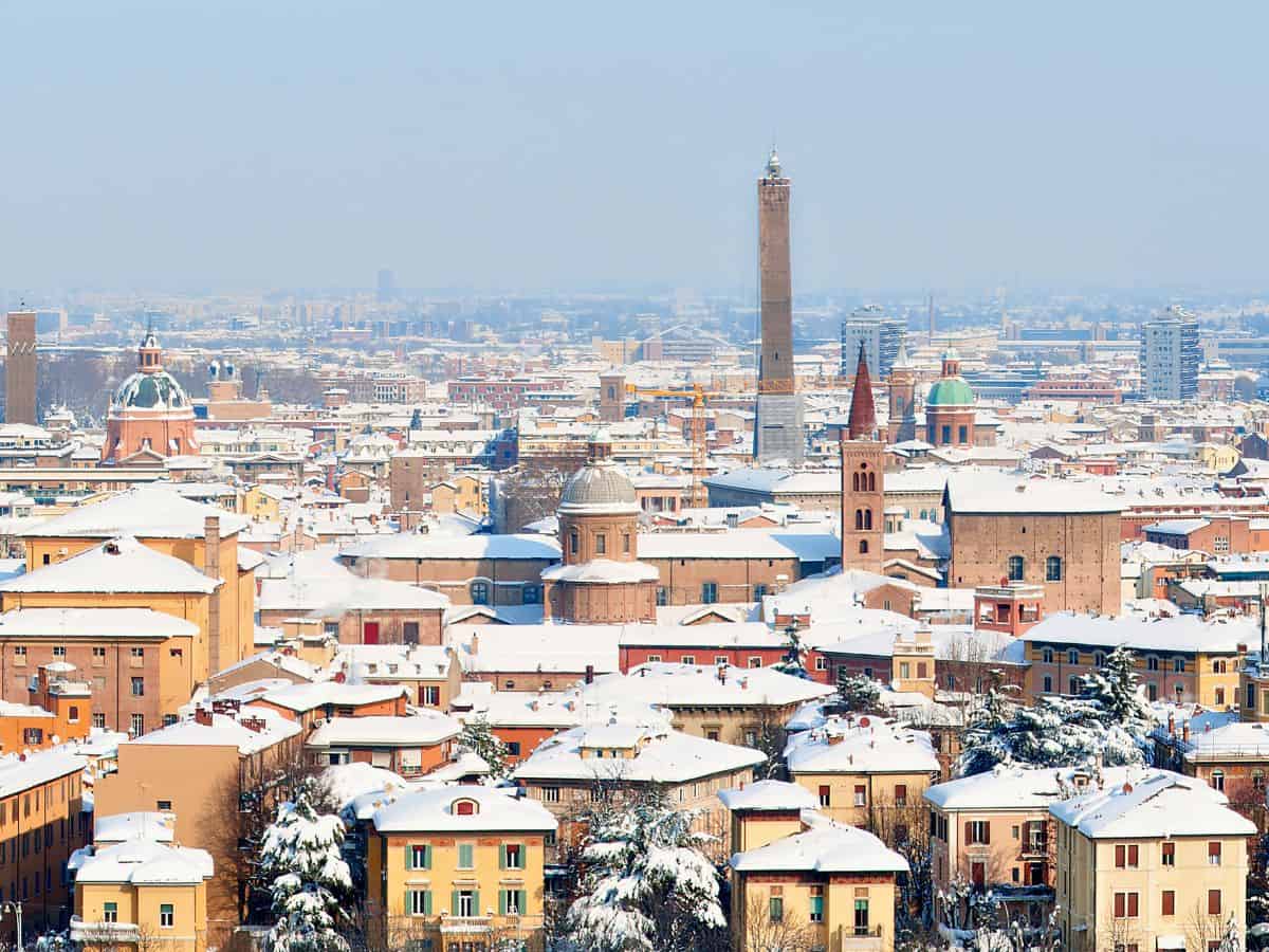 The city of Bologna from a distance with the roofs of the houses covered in snow.