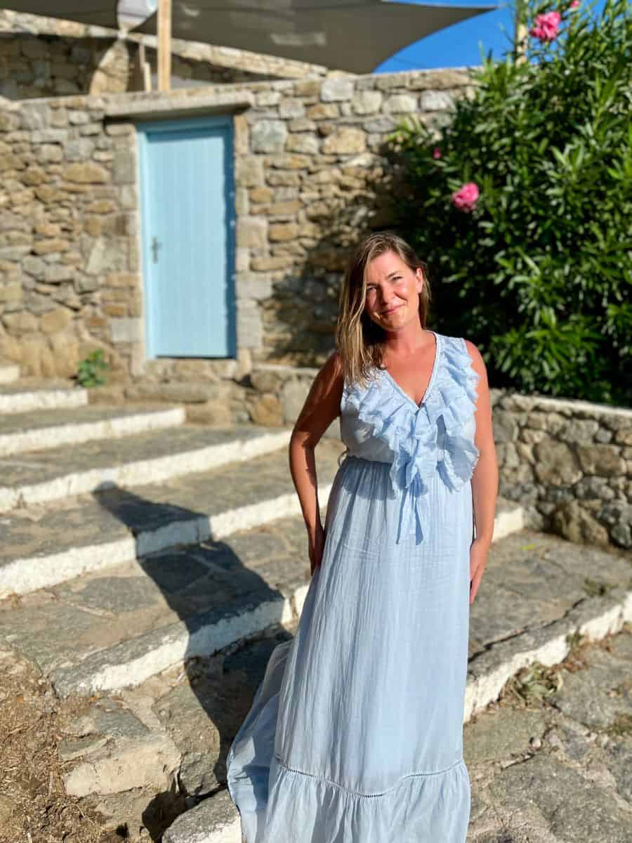 A woman alone on the island of Mykonos wearing a blue dress.