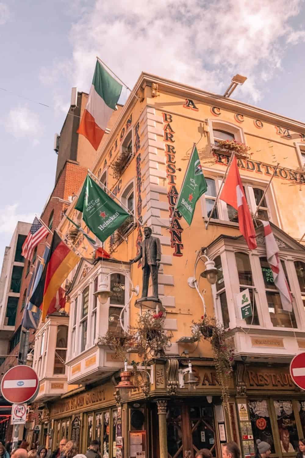 A colorful corner building in Dublin adorned with various international flags, including the Irish flag, capturing the city's welcoming spirit