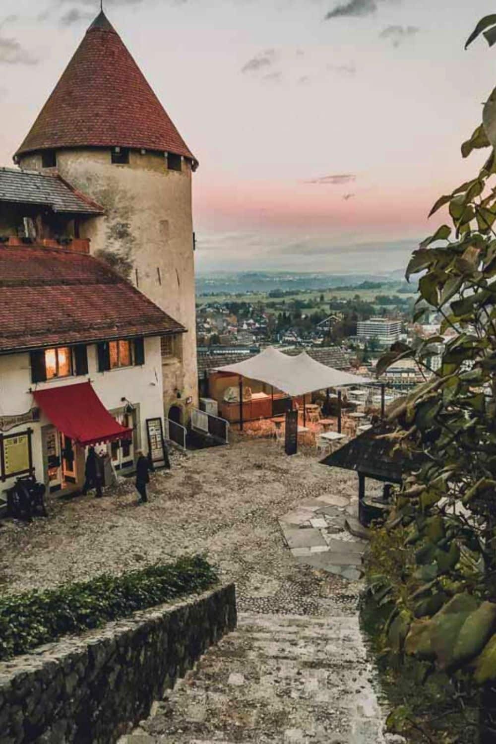 An evening view of a cobblestone courtyard with medieval buildings in Lake Bled, as the sky blushes at dusk, offering a historic ambiance for winter evening strolls.