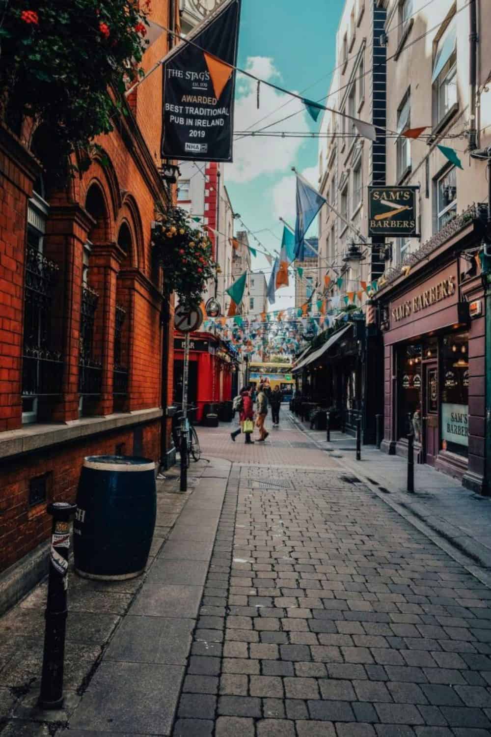 A picturesque view of a cobbled street in Dublin, lined with traditional red-brick buildings and colorful pubs, inviting solo travelers to explore its vibrant culture.