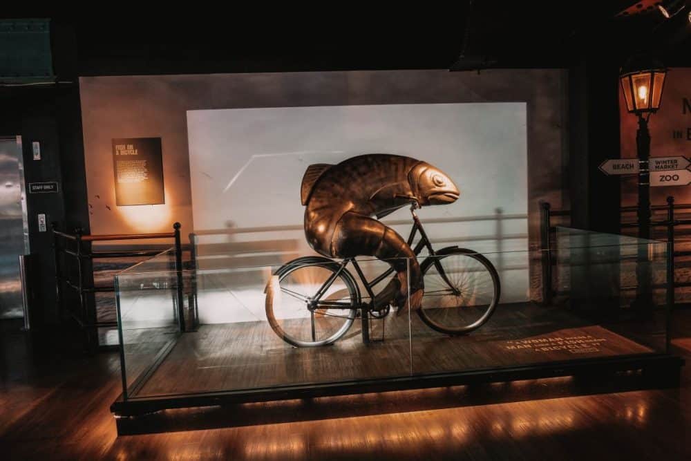 Quirky exhibit of a fish on a bicycle at a Guinness Factory, a playful display capturing the city's sense of humor and whimsy