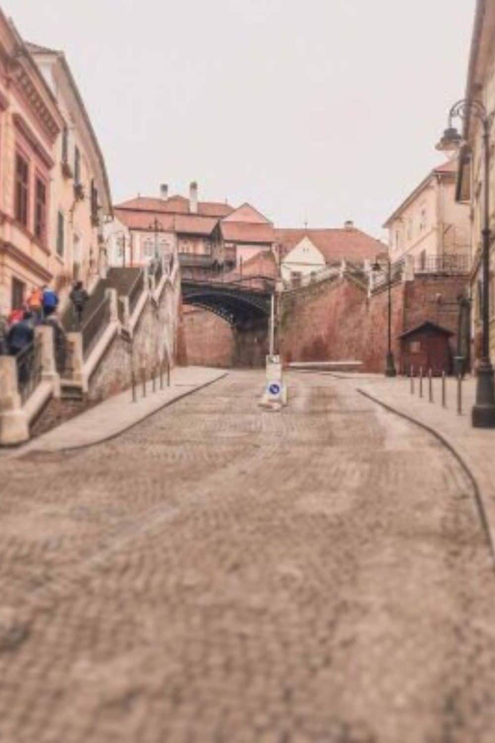 The iconic Liars' Bridge in Sibiu's historic center, with its cobblestone path and surrounding baroque buildings, a testament to why Sibiu is worth visiting.