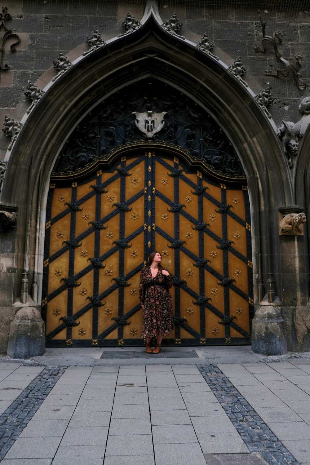 A solo traveler gazes up at the ornate Gothic gates of the New Town Hall in Munich, marveling at the city's rich historical tapestry