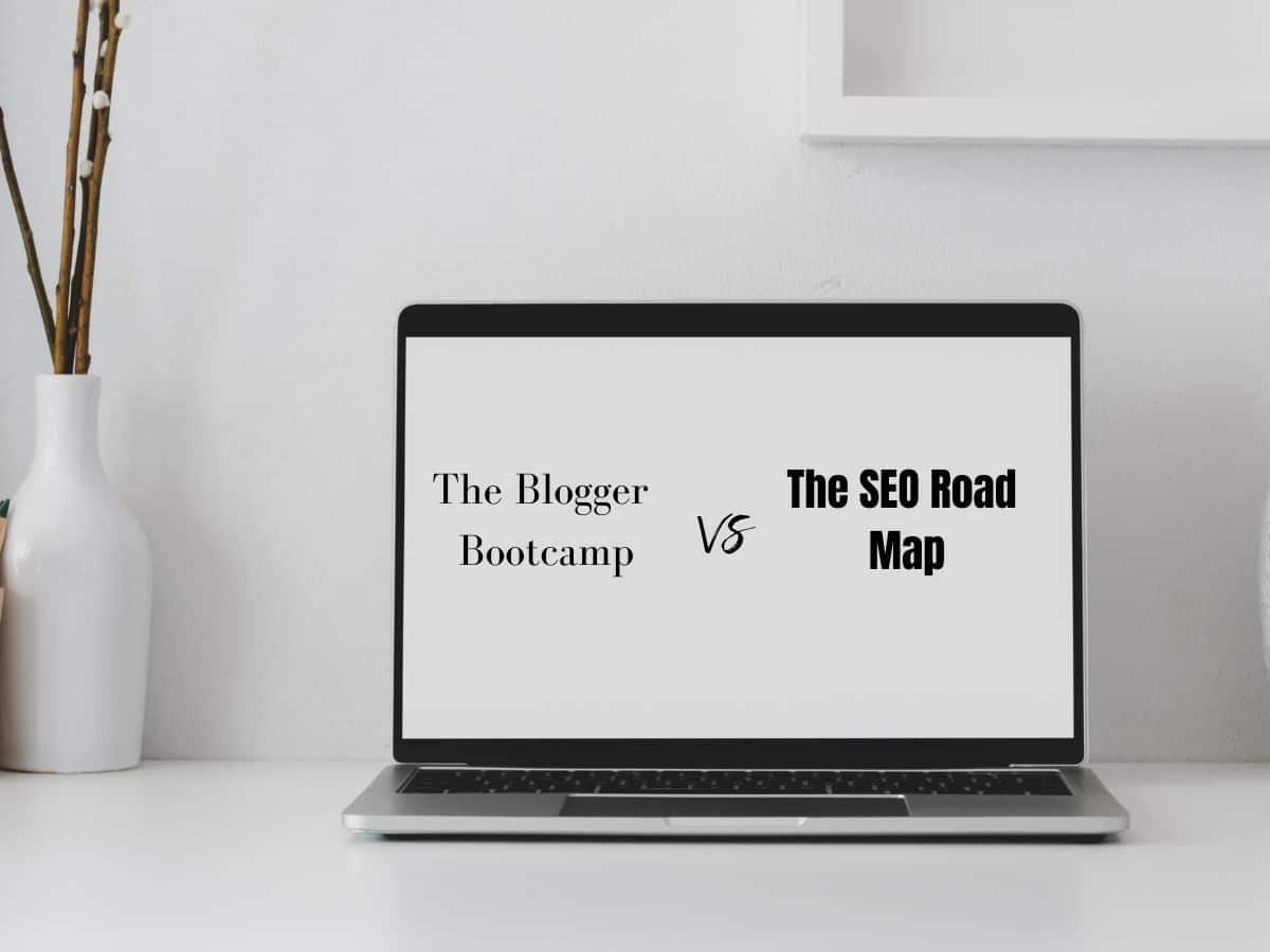 Laptop on a white desk showing 'The Blogger Bootcamp vs The SEO Road Map' on screen, with a vase and wall art in the background