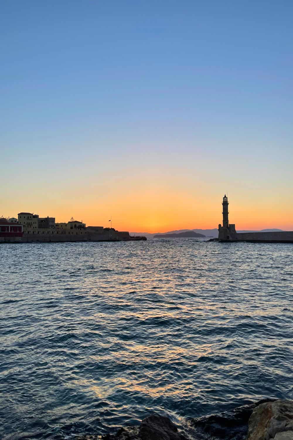 Lighthouse in Chania Harbor with sunset skies.