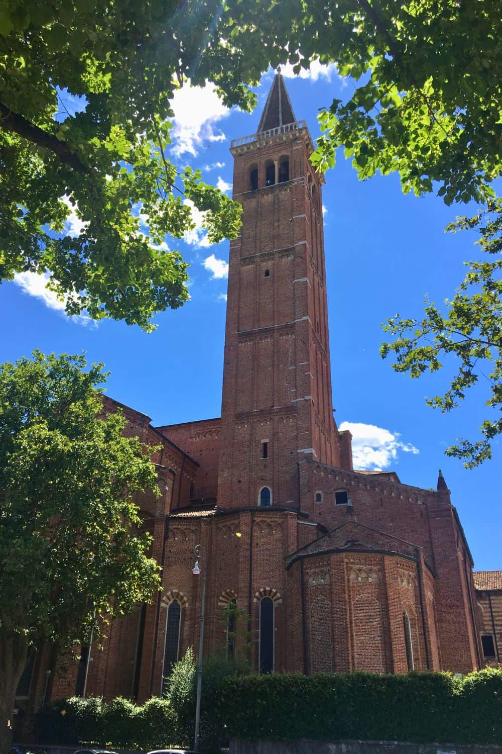 A red brick church on a sunny day with the lush green trees.