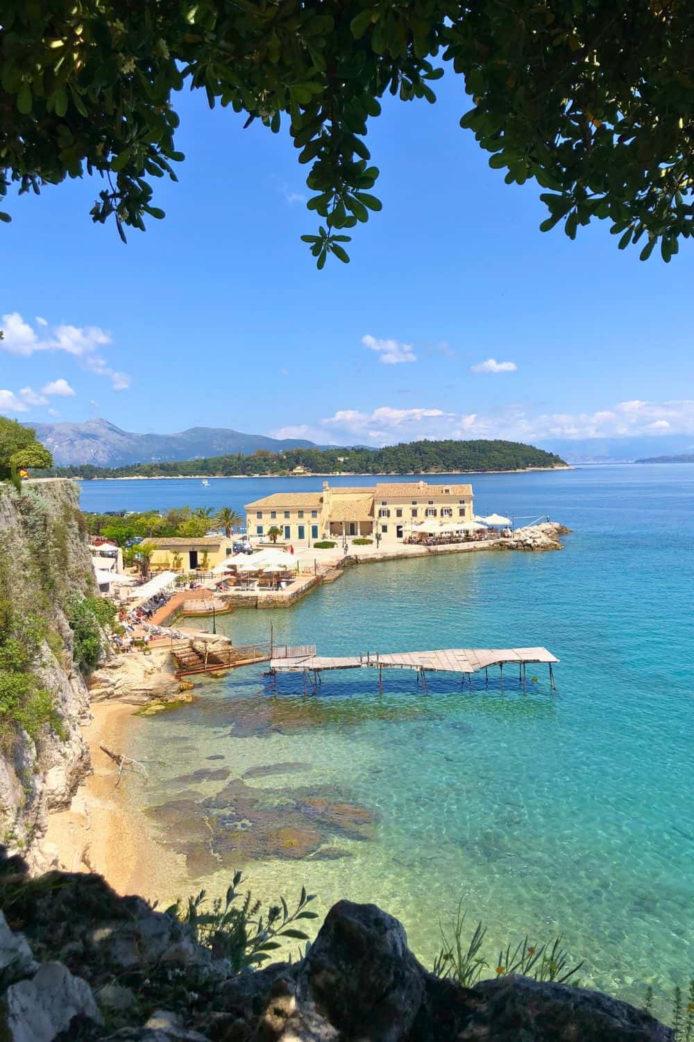 Colorful crystal blue water and large house in the background in Corfu, Greece.