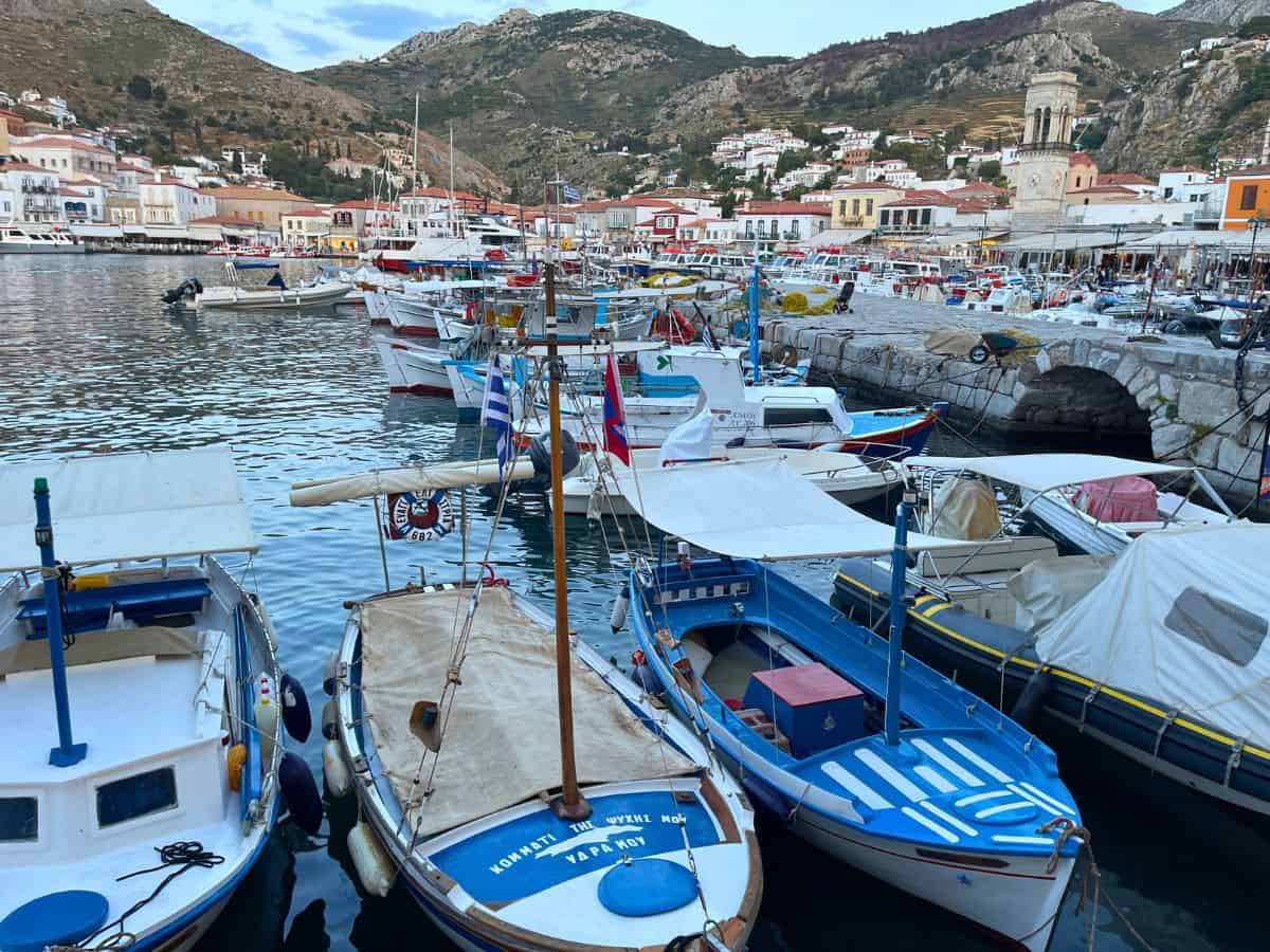 Small Greek fishing boats in the water with the Greek Island of Hydra in the background. 
