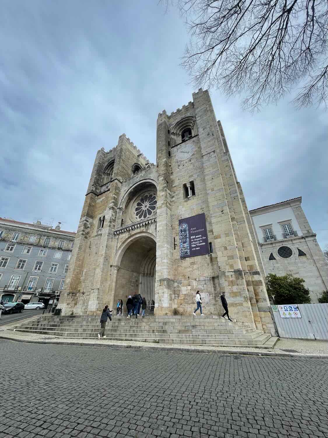 Visitors ascend the steps to the Lisbon Cathedral, a mix of Romanesque and Gothic architecture, reflecting the city's deep historical and religious heritage