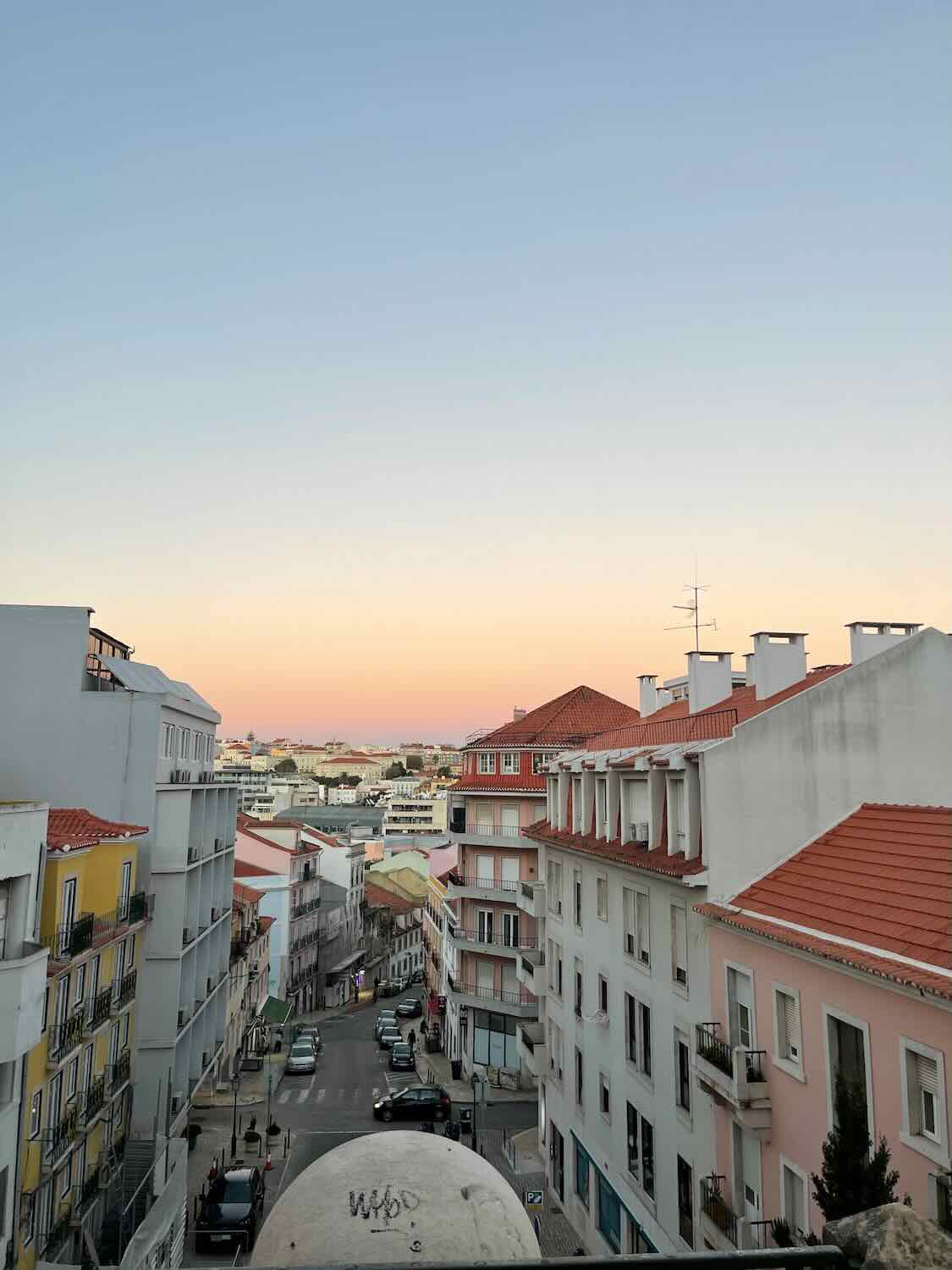 The streets of Lisbon bathed in the warm glow of sunset, highlighting the city's residential buildings and calm urban atmosphere.