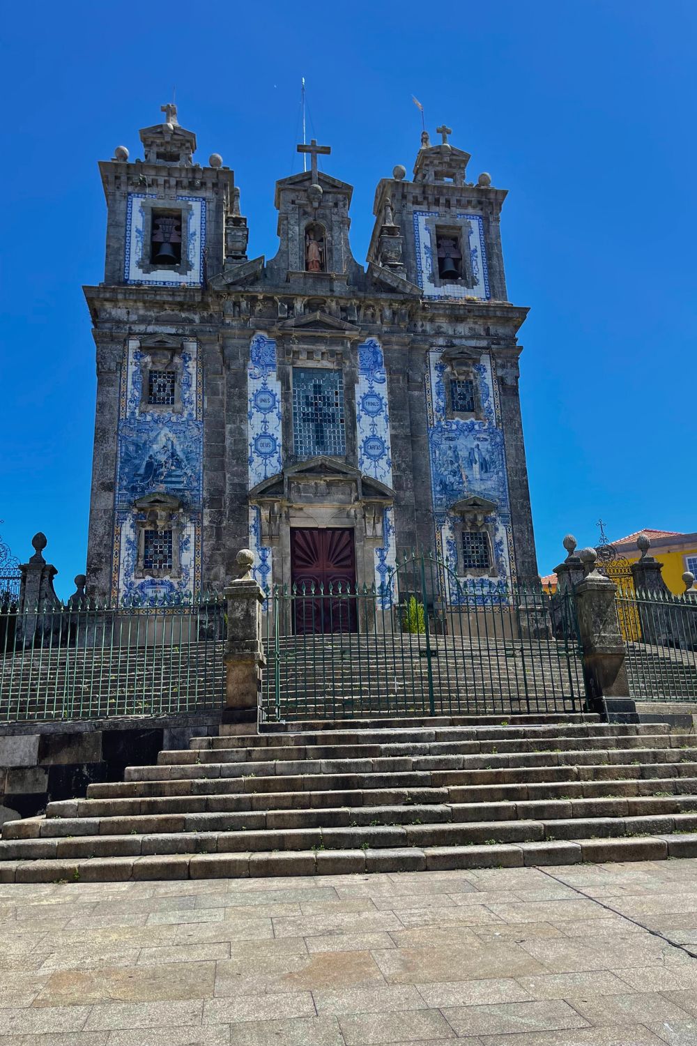 The iconic blue and white azulejo tiles adorn the facade of the historic Church in Porto, set against a clear blue sky, showcasing Portugal's traditional ceramic craftsmanship.