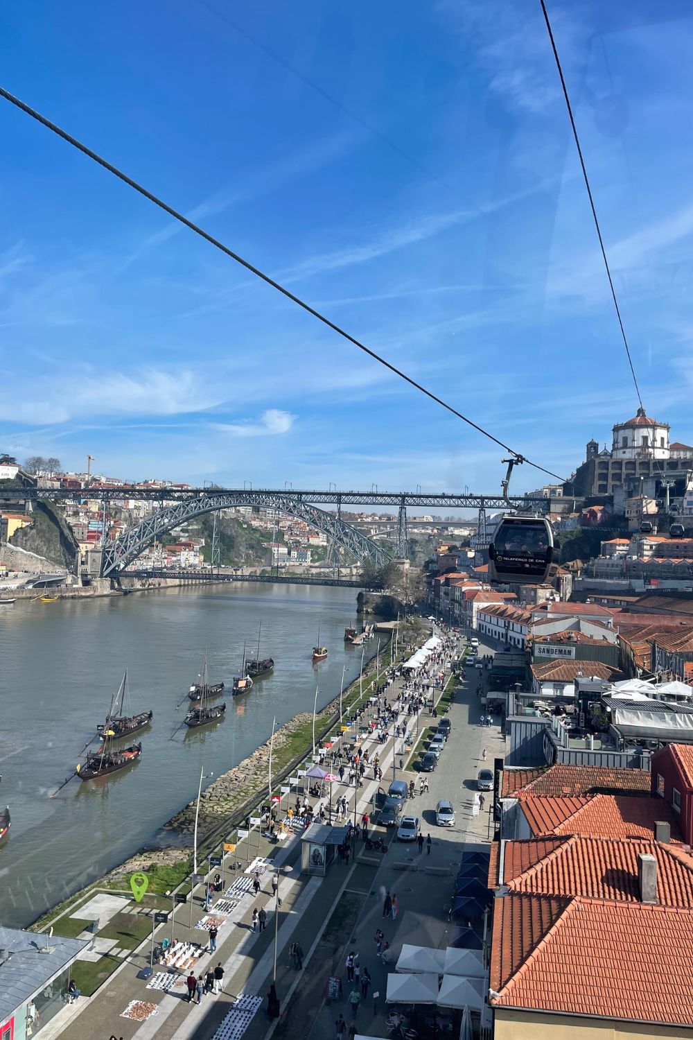 A cable car glides over the Douro River offering panoramic views of Porto's landscape, including the iconic double-decked Dom Luís I Bridge and traditional Rabelo boats.
