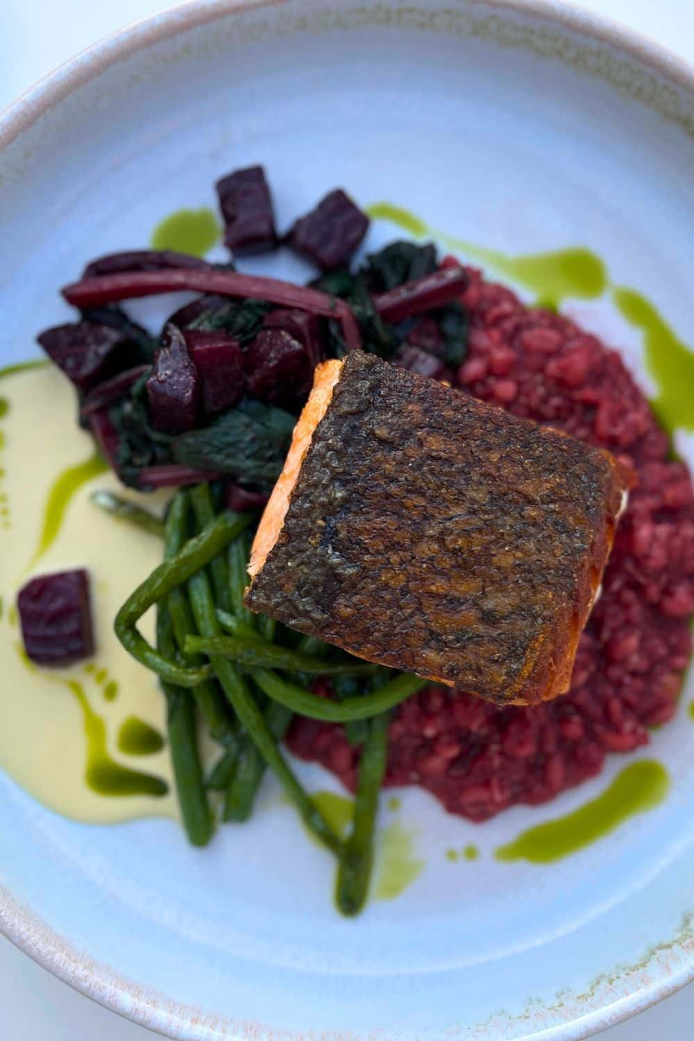 Deliciously prepared salmon served with beetroot and green beans over red rice, presented on a ceramic plate, showcasing Hydra's culinary delights.