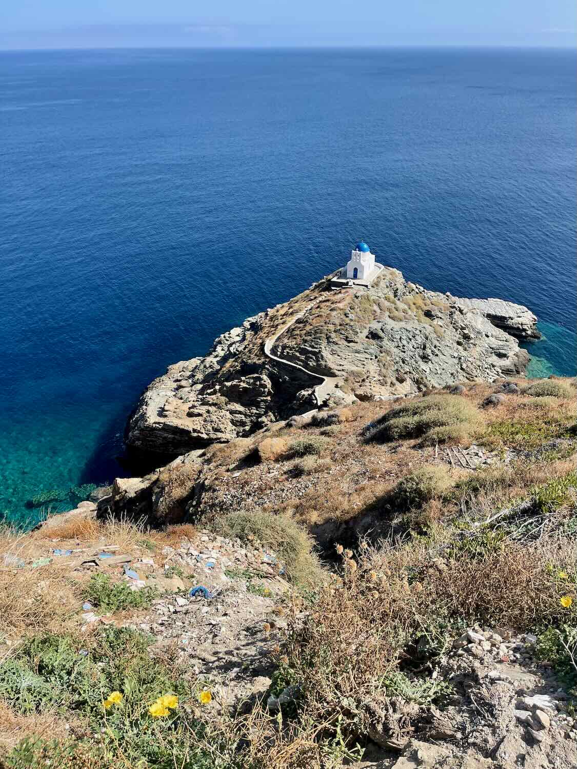 The iconic blue-domed church of Kastro perched on a rocky promontory jutting into the cerulean Aegean Sea, a must-see destination 
